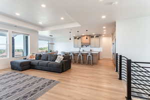 Living area with recessed lighting, light wood-type flooring, and a tray ceiling