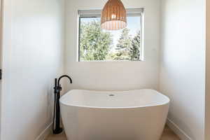 Full bath with a soaking tub and wood finished floors