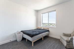 Bedroom featuring dark colored carpet and baseboards