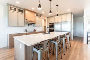 Kitchen with a breakfast bar area, pendant lighting, light stone counters, and recessed lighting