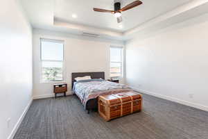 Bedroom featuring a raised ceiling, dark colored carpet, ceiling fan, and recessed lighting
