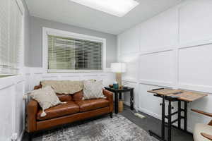Sitting room featuring a decorative wall, carpet, and a drop ceiling