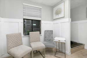 Living area featuring a decorative wall, wood finished floors, a wainscoted wall, and a drop ceiling