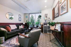 Living area with wainscoting, wood walls, a textured ceiling, light carpet, and recessed lighting