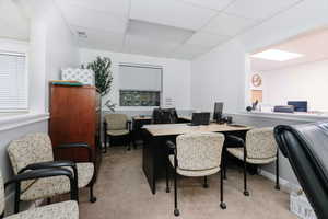 Dining area featuring a desk, light carpet, and a paneled ceiling