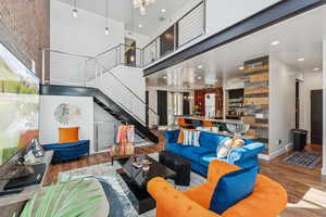 Living area with a chandelier, a towering ceiling, wood finished floors, stairway, and recessed lighting