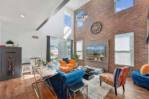 Living area with a towering ceiling, hardwood / wood-style flooring, and brick wall