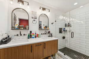 Bathroom with a stall shower, double vanity, and recessed lighting