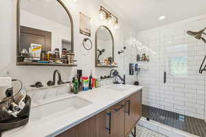 Full bath featuring a shower stall, double vanity, recessed lighting, and light tile patterned floors