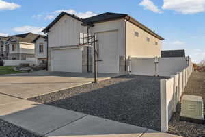 View of side of home with stone siding, board and batten siding, driveway, a gate, and a garage