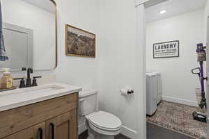 Bathroom featuring independent washer and dryer, vanity, and dark tile patterned floors
