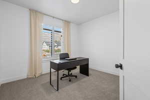 Home office with light colored carpet and baseboards