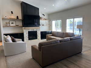Living area featuring wood finished floors, a fireplace, a textured ceiling, and recessed lighting