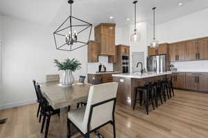Dining space featuring a chandelier, light wood-style flooring, recessed lighting, and a high ceiling