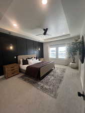Bedroom featuring a tray ceiling, light carpet, a ceiling fan, a textured ceiling, and recessed lighting