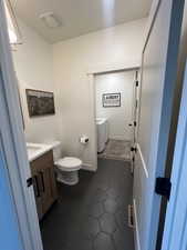 Bathroom featuring vanity, independent washer and dryer, and dark tile patterned flooring
