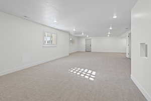 Basement featuring light carpet, recessed lighting, and a textured ceiling