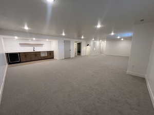 Unfurnished living room featuring light carpet and wet bar