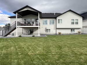 Rear view of property with a patio area, stucco siding, stairs, and a lawn