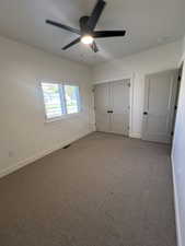 Unfurnished bedroom with carpet, a closet, and a ceiling fan