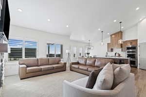 Living room featuring recessed lighting, high vaulted ceiling, and light colored carpet