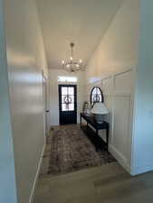 Doorway to outside with lofted ceiling and a chandelier