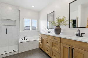 Bathroom with double vanity, a garden tub, a stall shower, and dark tile patterned flooring