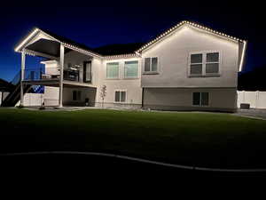 Back of house at twilight featuring a patio, stairs, and stucco siding