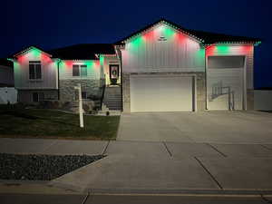 View of front of property featuring board and batten siding, stone siding, concrete driveway, a yard, and an attached garage