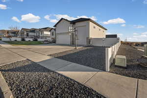 View of side of home featuring board and batten siding, driveway, a residential view, an attached garage, and a gate
