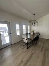 Dining room featuring plenty of natural light, light wood-style flooring, a chandelier, and lofted ceiling