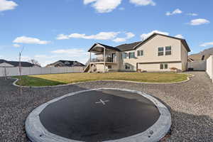 Back of house with a fenced backyard, a trampoline, a balcony, stucco siding, and a patio