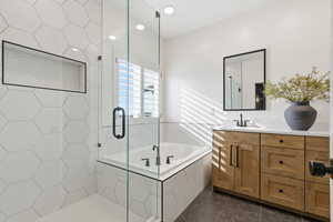 Bathroom featuring a bath, vanity, dark tile patterned flooring, and a stall shower