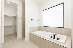 Bathroom featuring a spacious closet and a bath