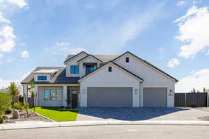 Modern farmhouse with board and batten siding, decorative driveway, and brick siding
