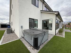 Rear view of house with a hot tub, stucco siding, and a patio
