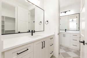 Full bath featuring vanity, light floors, and a walk in closet
