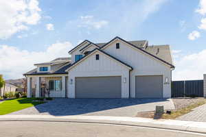 Modern farmhouse featuring decorative driveway, brick siding, board and batten siding, and an attached garage