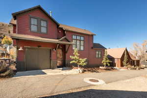 View of front facade with an attached garage, a shingled roof, and driveway