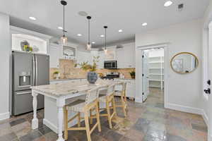 Kitchen featuring appliances with stainless steel finishes, decorative backsplash, pendant lighting, white cabinets, and recessed lighting