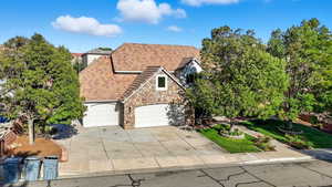 View of front of house featuring stone siding, concrete driveway, a front lawn, and a shingled roof