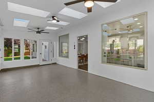 Unfurnished sunroom with speckled floor and a skylight