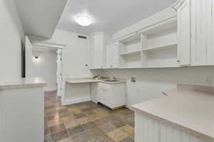 Laundry room with hookup for a washing machine, stone finish flooring, and cabinet space