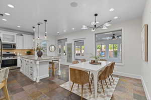 Dining space with recessed lighting, stone tile flooring, a chandelier, and a ceiling fan