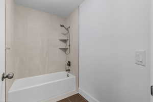 Bathroom with dark tile patterned floors and shower / bathtub combination