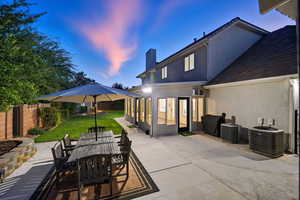 Patio terrace at dusk featuring outdoor dining area, a fenced backyard, a patio, and a sunroom
