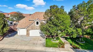 View of front of home with stone siding, a front yard, concrete driveway, and a garage