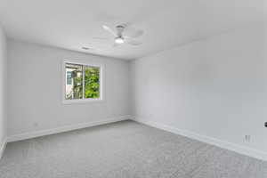 Spare room featuring light colored carpet and a ceiling fan