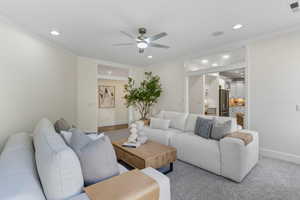 Carpeted living room with a ceiling fan, ornamental molding, and recessed lighting