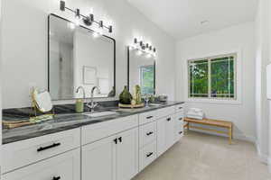Full bath with double vanity, plenty of natural light, a shower stall, and light tile patterned floors